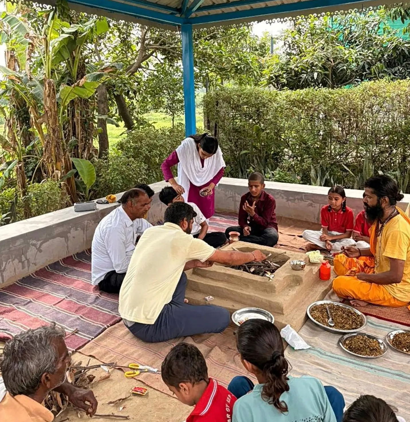 A teacher guiding students during preparations for the Yajna ceremony