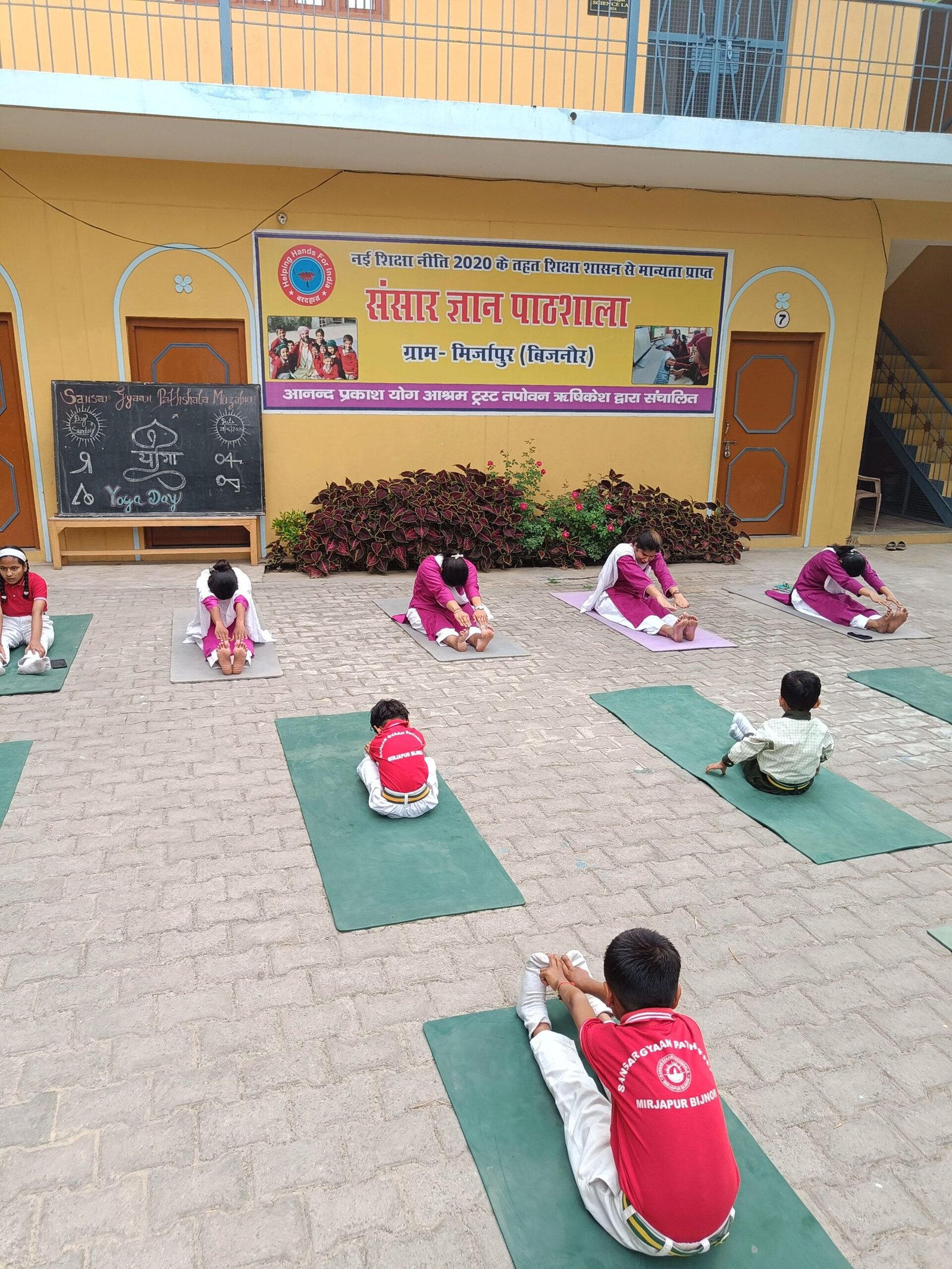 A student practicing a seated forward bend on Yoga Day